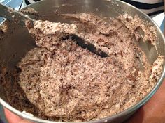 a person holding a metal bowl filled with batter and brown sugar on top of it