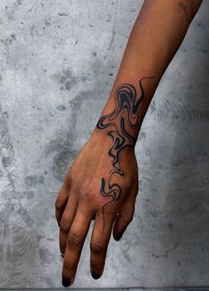 a person's hand with a black and white tattoo design on the left wrist