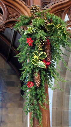 a cross decorated with pine cones and greenery