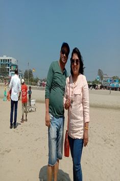 a man and woman standing on top of a sandy beach