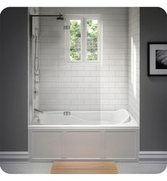 a bathroom with a white bath tub sitting next to a wooden floor and framed pictures on the wall