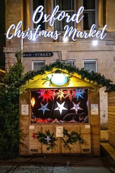 an outdoor christmas market with lights and decorations on the side of it, in front of a building