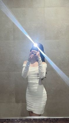 a woman taking a selfie in front of a mirror with light coming from her head