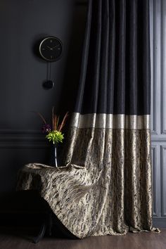 a black and gold drapes in front of a wall with a clock on it