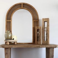 a wooden table topped with a mirror and vase