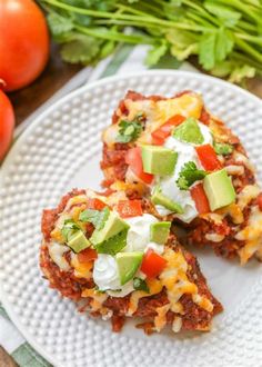 two mexican cakes on a white plate with tomatoes and lettuce next to it