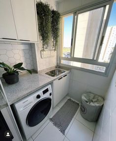 a kitchen with a washer and dryer in it next to a window filled with plants