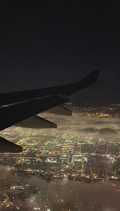 an airplane wing flying over a city at night