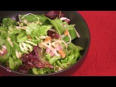 a salad with lettuce and red onions in a black bowl on a red tablecloth