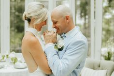 a bride and groom are smiling at each other in front of a table with white linens