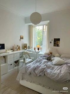 a bedroom with a bed, desk and computer on the table in front of a window