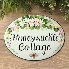 a sign that says, honeysuckle cottage with flowers and a bee on it