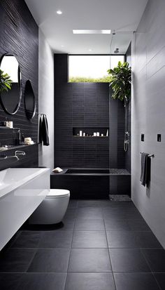 a black and white bathroom with two round mirrors on the wall above the bathtub