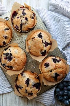 six blueberry muffins sitting on top of a table next to some berries