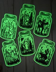 glow in the dark stickers depicting jars with animals and trees inside, on a wooden surface