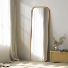 a mirror sitting on top of a wooden floor next to a window