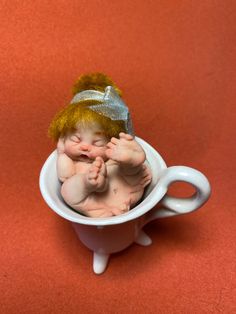 a baby doll in a coffee cup on a red background