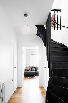 a black and white staircase leading up to a living room with a couch on the other side