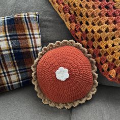 two crocheted pillows sitting on top of a gray couch next to each other