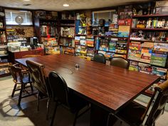 a room filled with lots of books and chairs next to a table in front of a book shelf