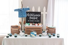 a table topped with cakes and cupcakes next to a sign