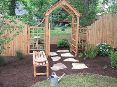 a garden area with a wooden arbor and stone stepping path leading to the back yard