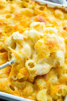 macaroni and cheese casserole in a white dish with a serving spoon