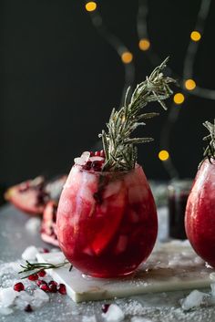 two pomegranate cocktails with rosemary sprigs on top