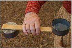 a person holding a wooden stick with two cups on it