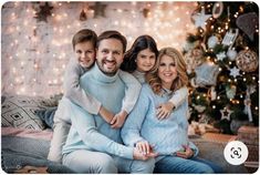 a man and two women sitting on a couch with their arms around each other in front of a christmas tree