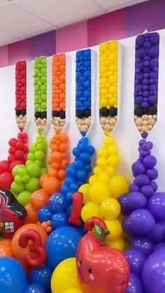 there are many different colored balloons on the wall and in front of them is a candy bar