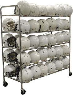 a bunch of white helmets are stacked on a metal rack with two football helmets in the middle