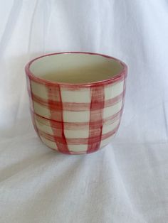 a red and white checkered bowl sitting on top of a tablecloth covered surface