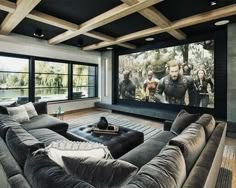 a large living room with couches and a big screen tv on the wall in front of it