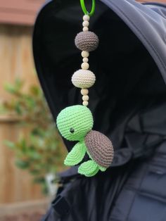 a crocheted turtle mobile hanging from a green and white string on a black jacket