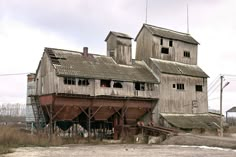 an old wooden building sitting on top of a dirt field