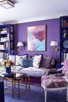 a living room with purple walls and furniture in the center, bookshelves on either side