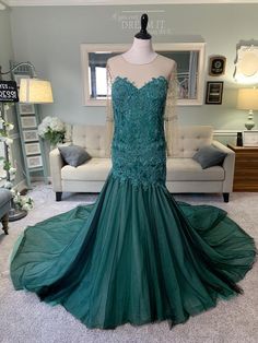 a dress on display in a room with a couch and chair behind the mannequin