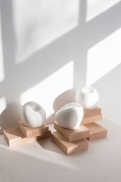 three white vases sitting on top of wooden blocks in front of a large window