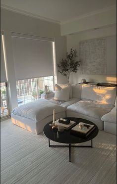 a living room with a large white couch and coffee table in front of the window