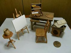 an assortment of miniature wooden chairs and desks on a white table with a penny