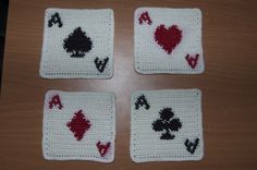 four crocheted coasters with playing cards on them sitting on a wooden table