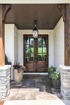 a front door with two planters on each side and a lantern hanging from the ceiling