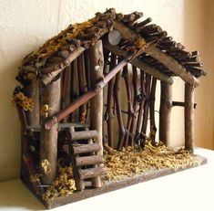 a nativity scene made out of wood sticks and logs, with a small house in the middle