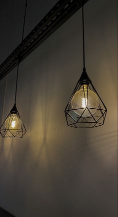 three light fixtures hanging from the ceiling in a dimly lit room with shadows on the wall