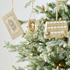 two ornaments are hanging from a christmas tree, one is gold and the other is white