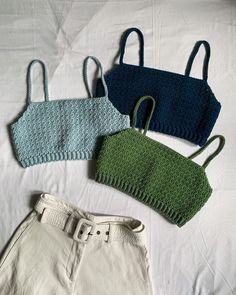 three knitted bags sitting on top of a bed