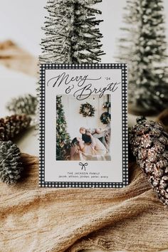 a christmas card sitting on top of a table next to pine cones