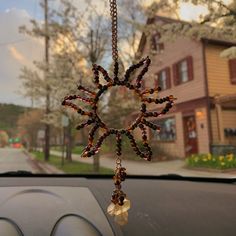 a car dashboard with a wind chime hanging from it's center window, in front of a house