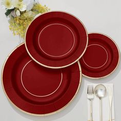 three red plates with gold rims and silverware